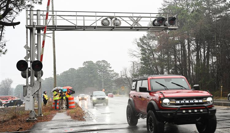 SUV driving over rail road tracks in the rain.