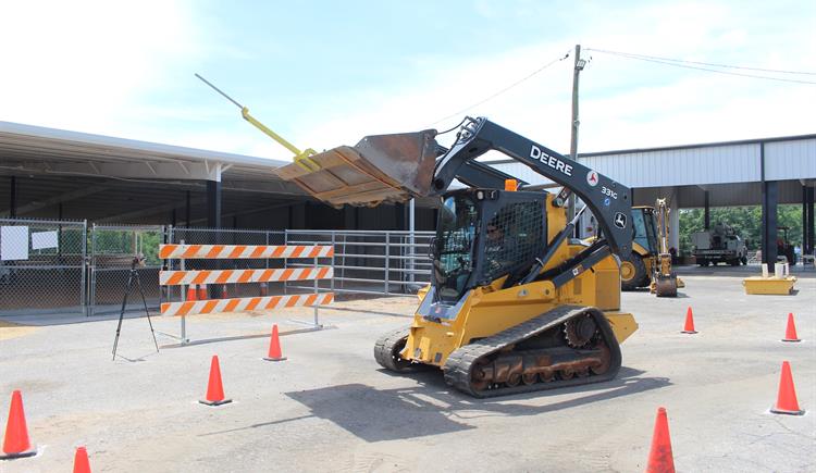 A woman operates a skid-steer in an obstacle course at the Cleveland County Fairgrounds.