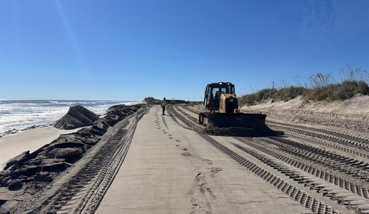 A NCDOT crew works to push sand off of NC 12