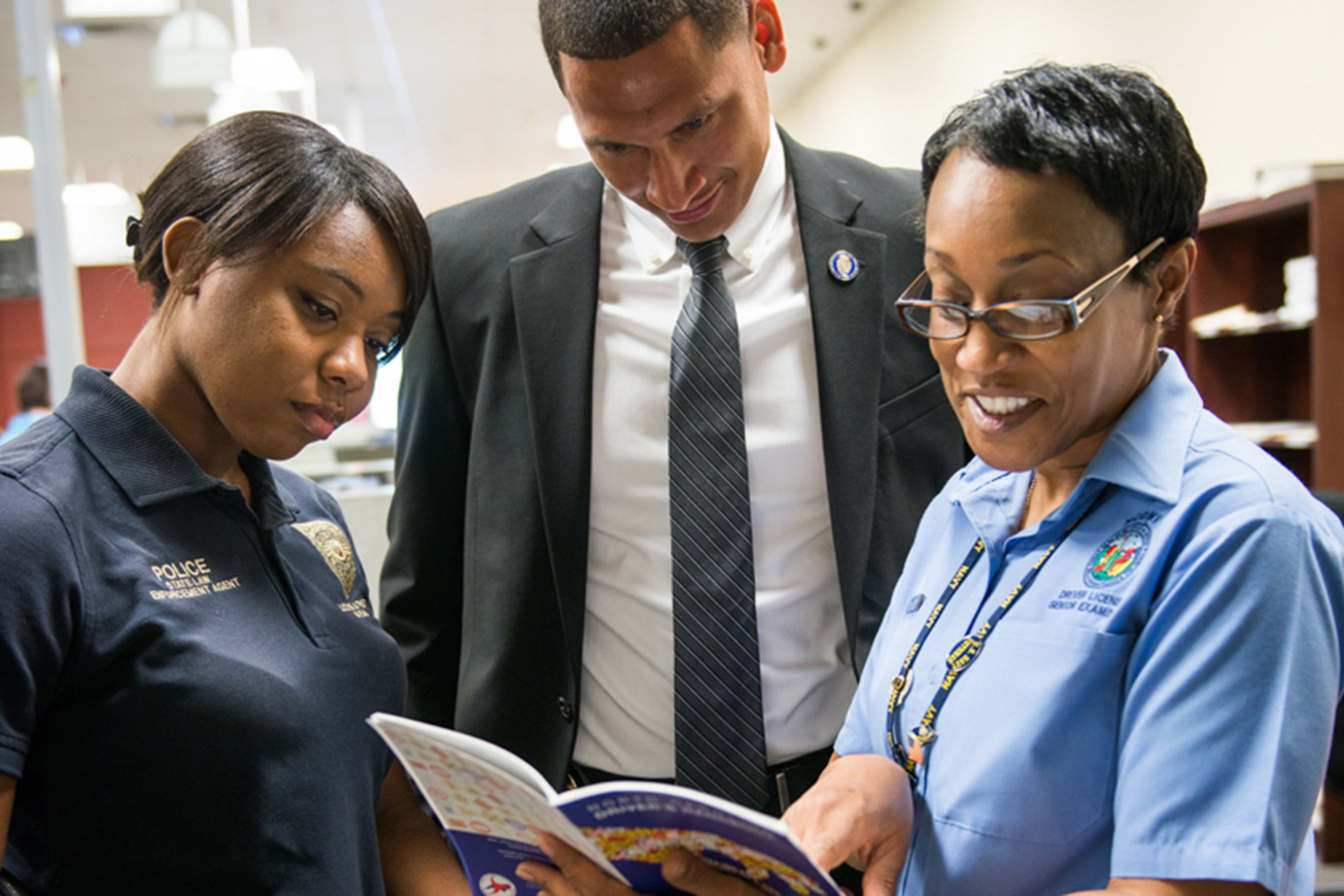 Three individuals reading from a workbook